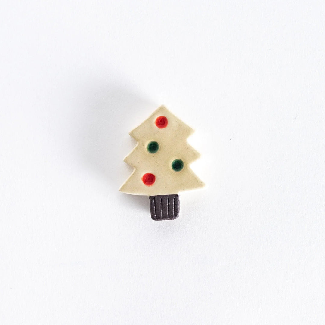 A ceramic chopsticks rest shaped like a white Christmas tree with red and green ornaments.