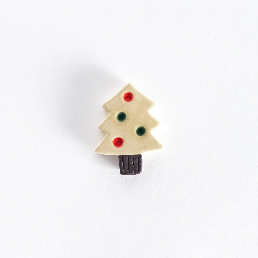 A ceramic chopsticks rest shaped like a white Christmas tree with red and green ornaments.