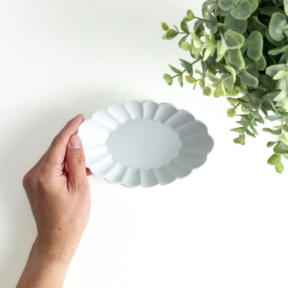 A white porcelain oval dessert bowl with a scalloped design.