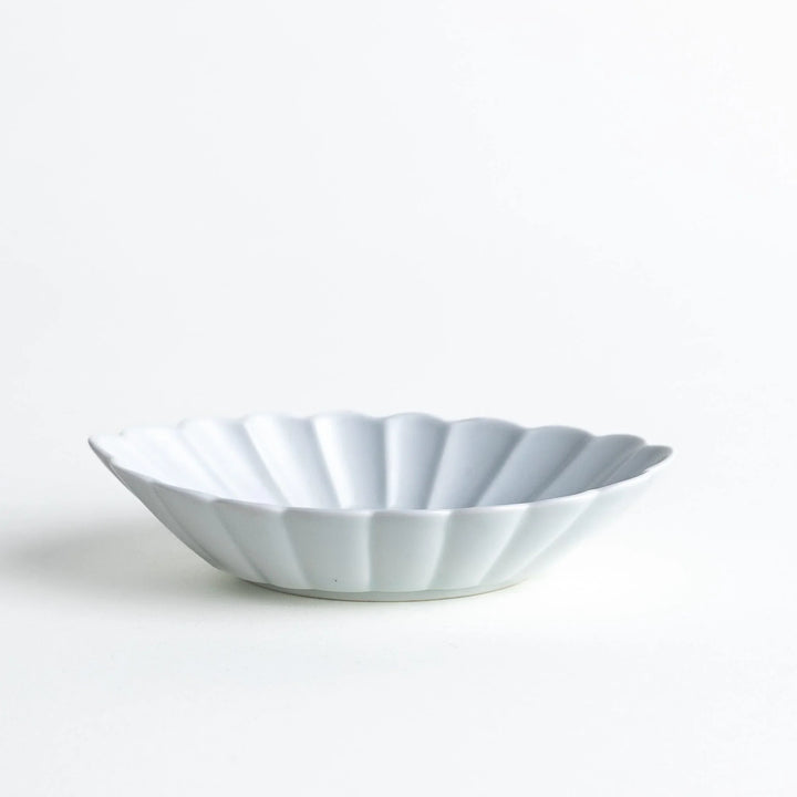 A white porcelain oval dessert bowl with a scalloped design.
