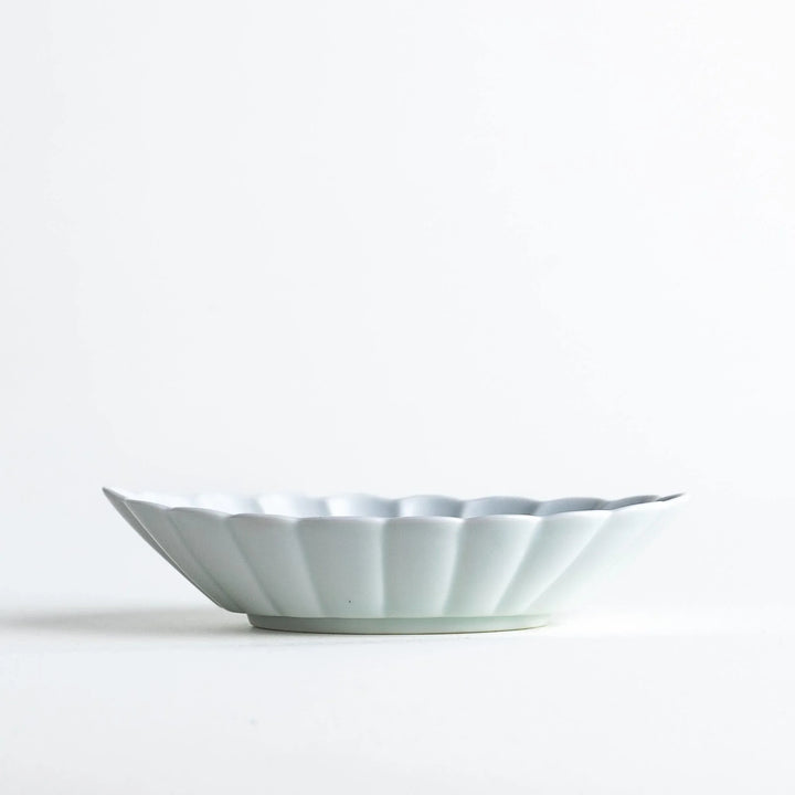 A white porcelain oval dessert bowl with a scalloped design.