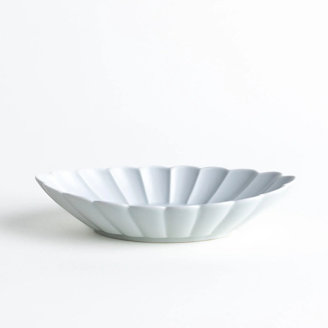 A white porcelain oval pasta bowl with a scalloped design.