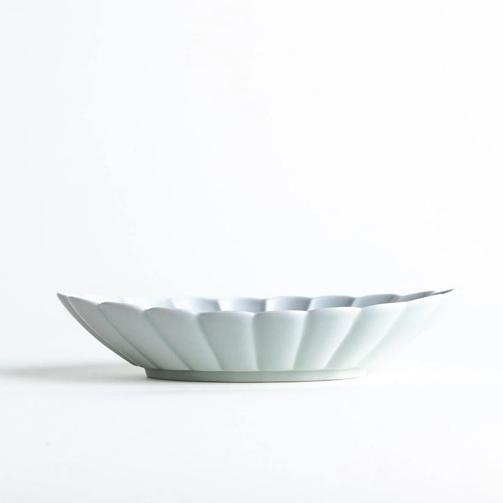 A white porcelain oval pasta bowl with a scalloped design.