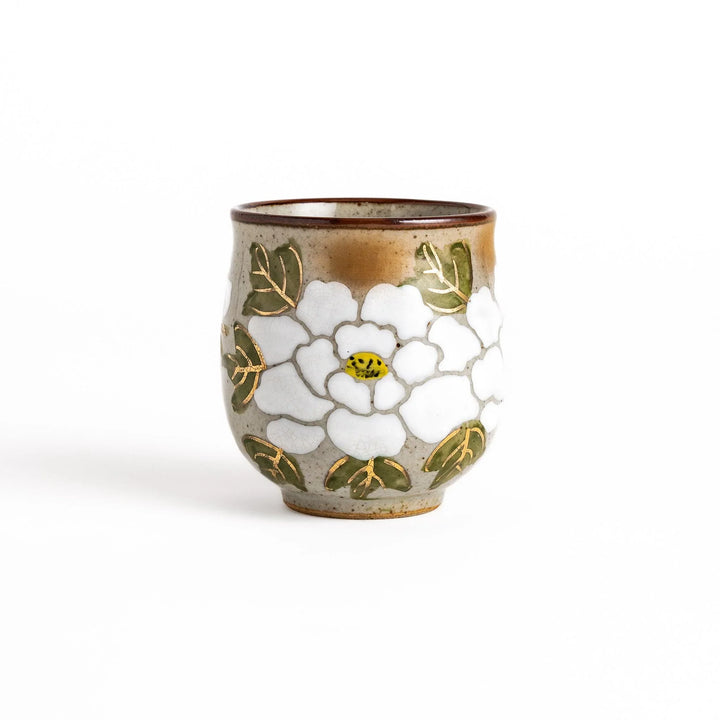 Ceramic teacup with a delicate white flower design and green leaves, perfect for enjoying a peaceful moment with tea.