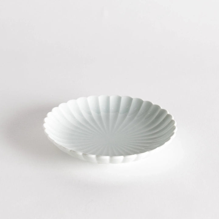 A simple white ceramic plate with a scalloped edge and a clean, minimalist design.