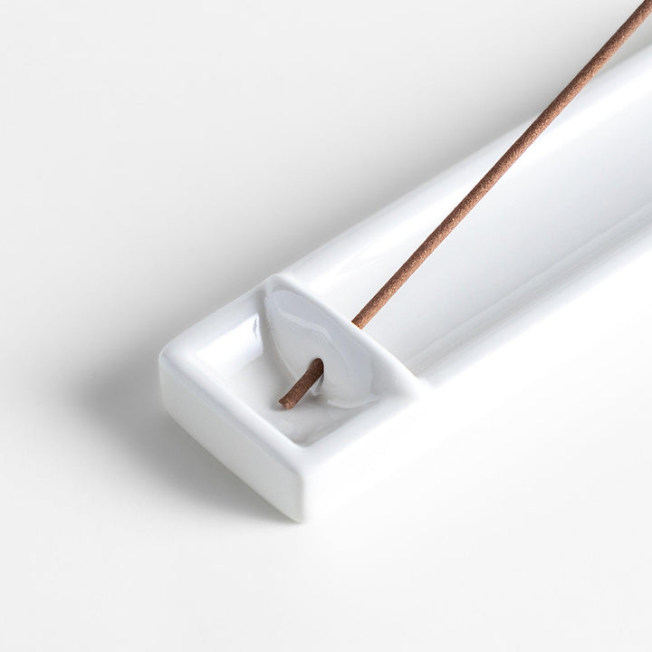 Minimalist white ceramic Japanese incense holder with rectangular shape and slot for clean ash catching.