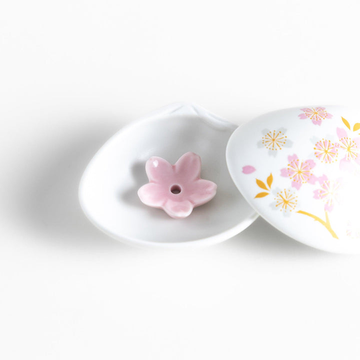 White seashell-shaped incense holder with pink and gold sakura details and blossom stand for a refined touch.