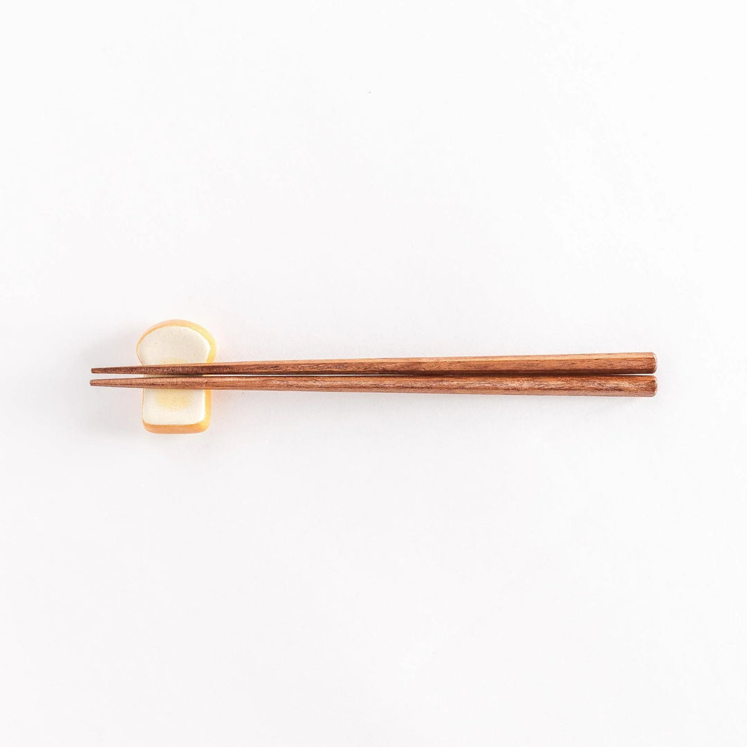 The toast-shaped chopsticks rest with chopsticks on top, photographed from a distance.