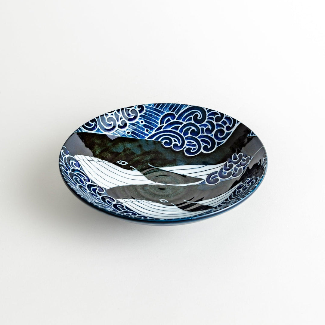 A pasta bowl decorated with blue and white whales and waves.