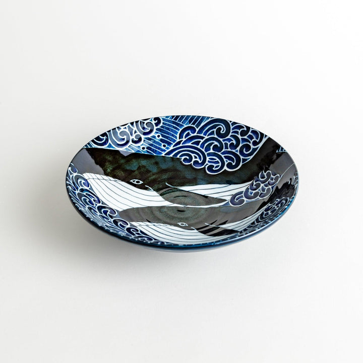 A pasta bowl decorated with blue and white whales and waves.