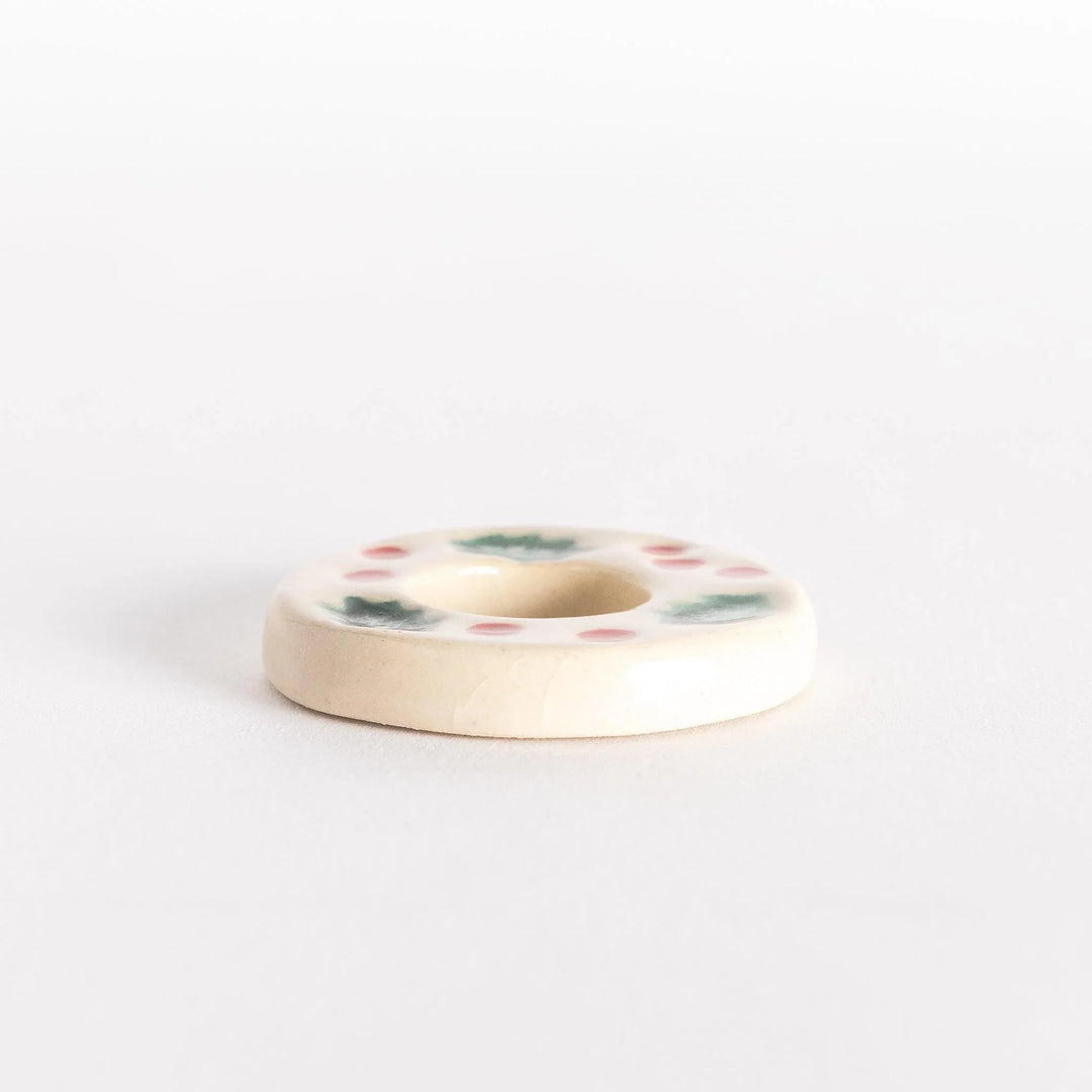 A side view of the ceramic wreath chopstick rest, highlighting its raised edges and festive design elements.