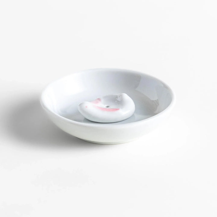 White ceramic incense holder set with round dish and rabbit holder with pink accents for charming ash collection.