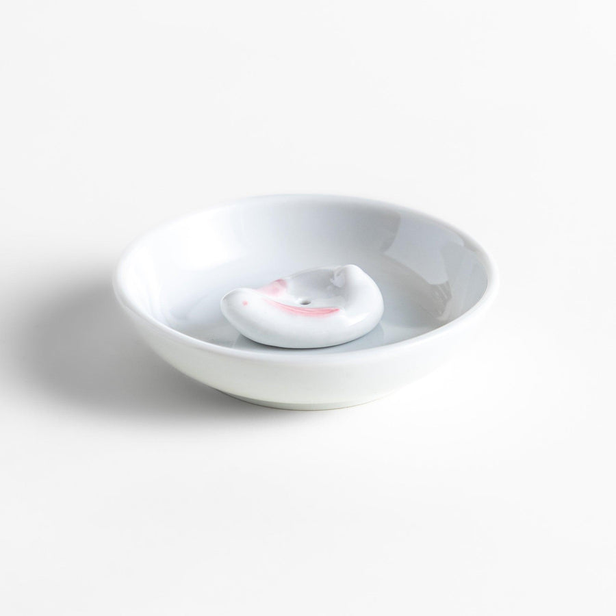 White ceramic incense holder set with round dish and rabbit holder with pink accents for charming ash collection.