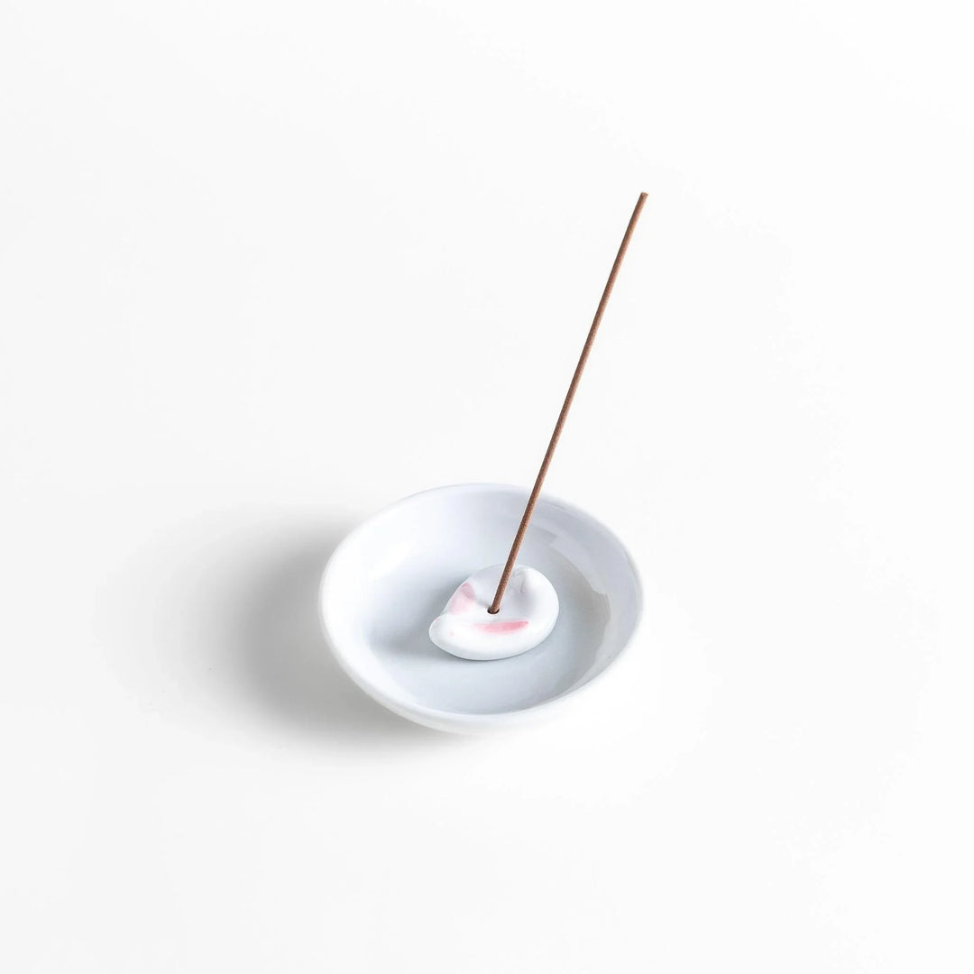 White ceramic incense holder set with round dish and rabbit holder with pink accents for charming ash collection.