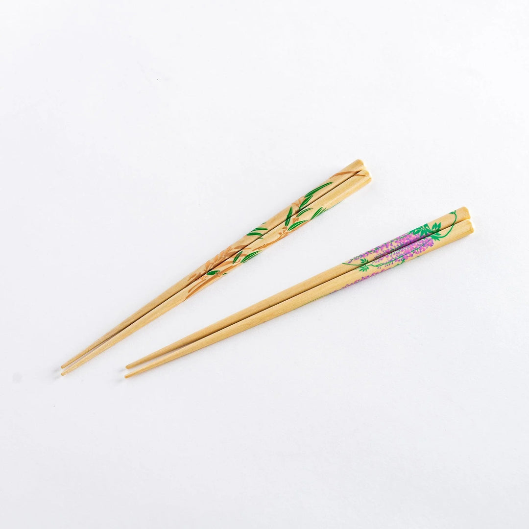 Elegant chopsticks with wisteria and bamboo motifs in wooden box with blue background for gifting.