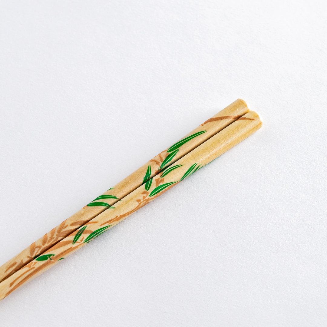 Elegant chopsticks with wisteria and bamboo motifs in wooden box with blue background for gifting.
