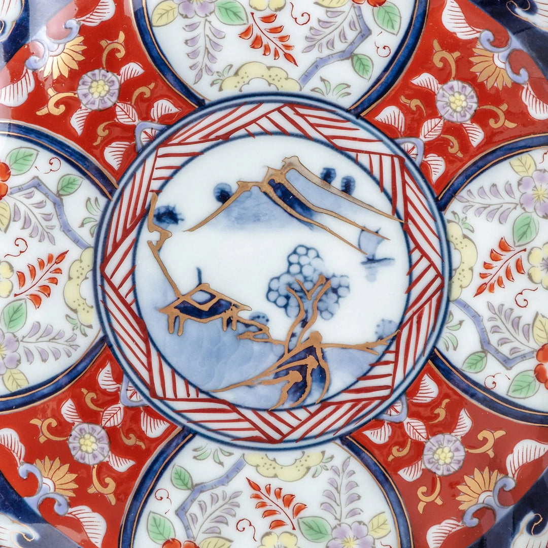 Small scalloped porcelain bowl with Imari style decoration central landscape and red blue rim motifs.