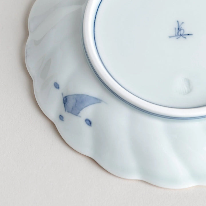 Small scalloped porcelain bowl with Imari style decoration central landscape and red blue rim motifs.