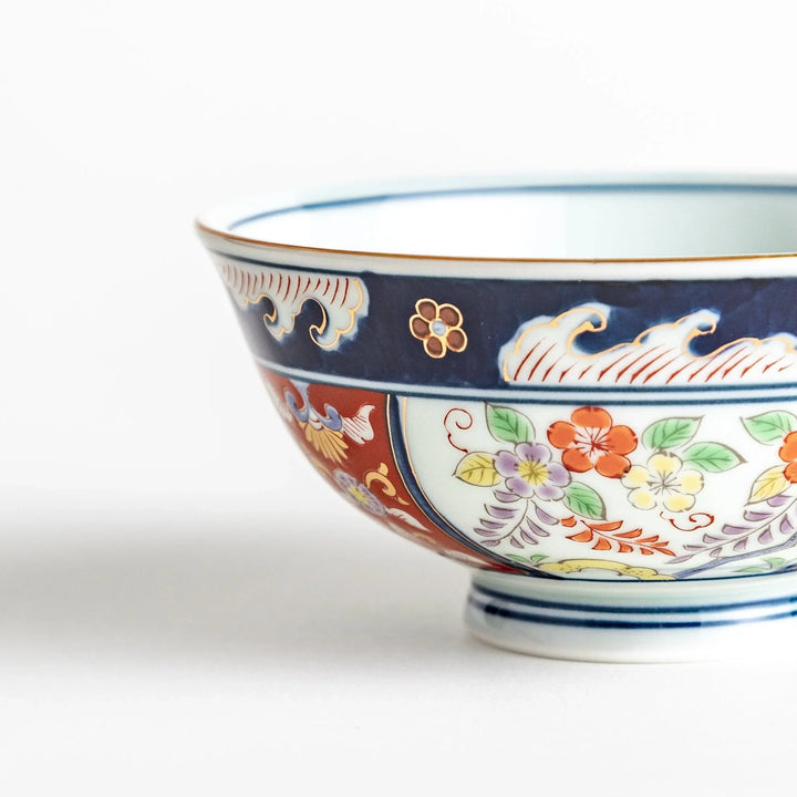 Porcelain bowl with traditional Japanese floral and geometric motifs in blue red and green with gold accents.