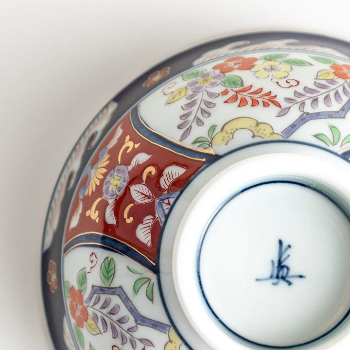 Porcelain bowl with traditional Japanese floral and geometric motifs in blue red and green with gold accents.