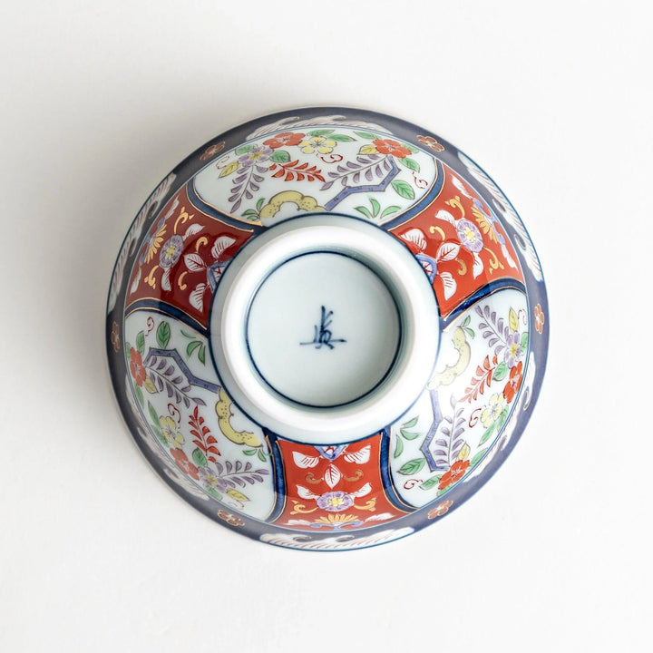 Porcelain bowl with traditional Japanese floral and geometric motifs in blue red and green with gold accents.
