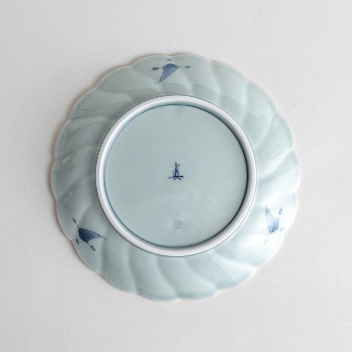 Scalloped porcelain bowl with Imari style red and blue alternating patterns and central landscape motif.