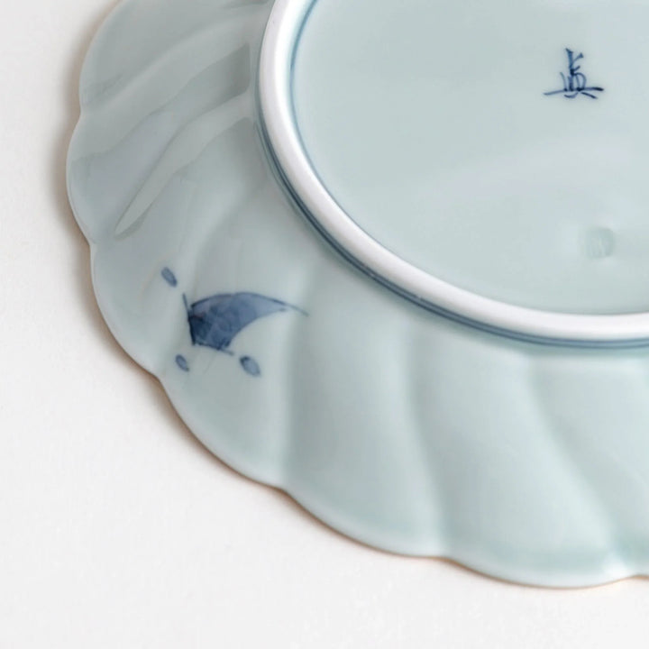 Scalloped porcelain bowl with Imari style red and blue alternating patterns and central landscape motif.