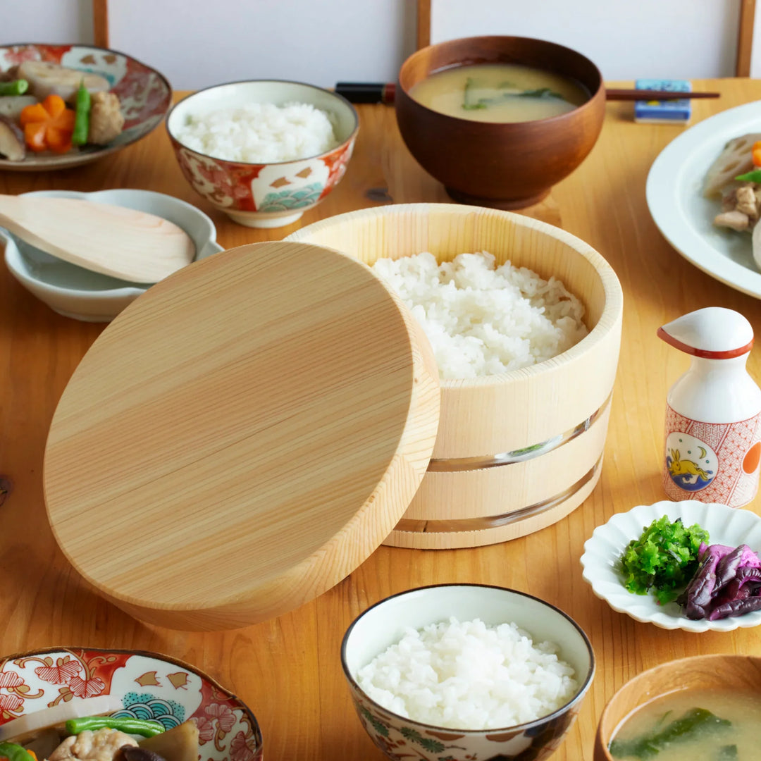 Wooden ohitsu rice bowl filled with rice, paired with miso soup and sides for a cozy Japanese meal.