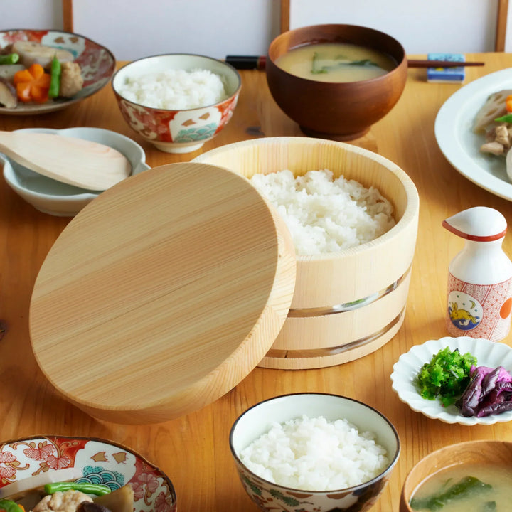 Wooden ohitsu rice bowl filled with rice, paired with miso soup and sides for a cozy Japanese meal.