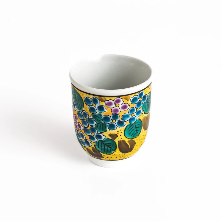Yellow teacup with a colorful hydrangea pattern and green leaves, perfect for enjoying a cup of tea.