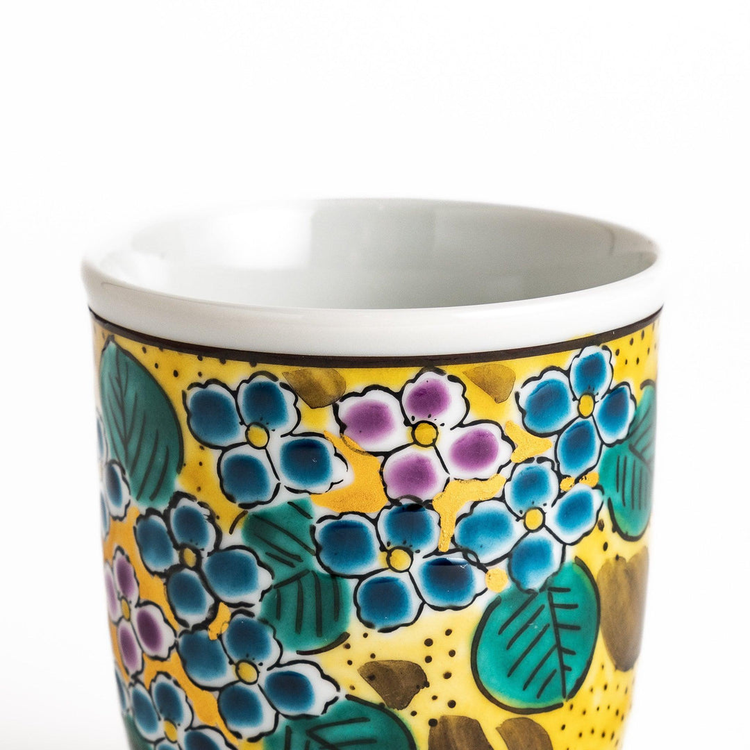 Yellow teacup with a colorful hydrangea pattern and green leaves, perfect for enjoying a cup of tea.