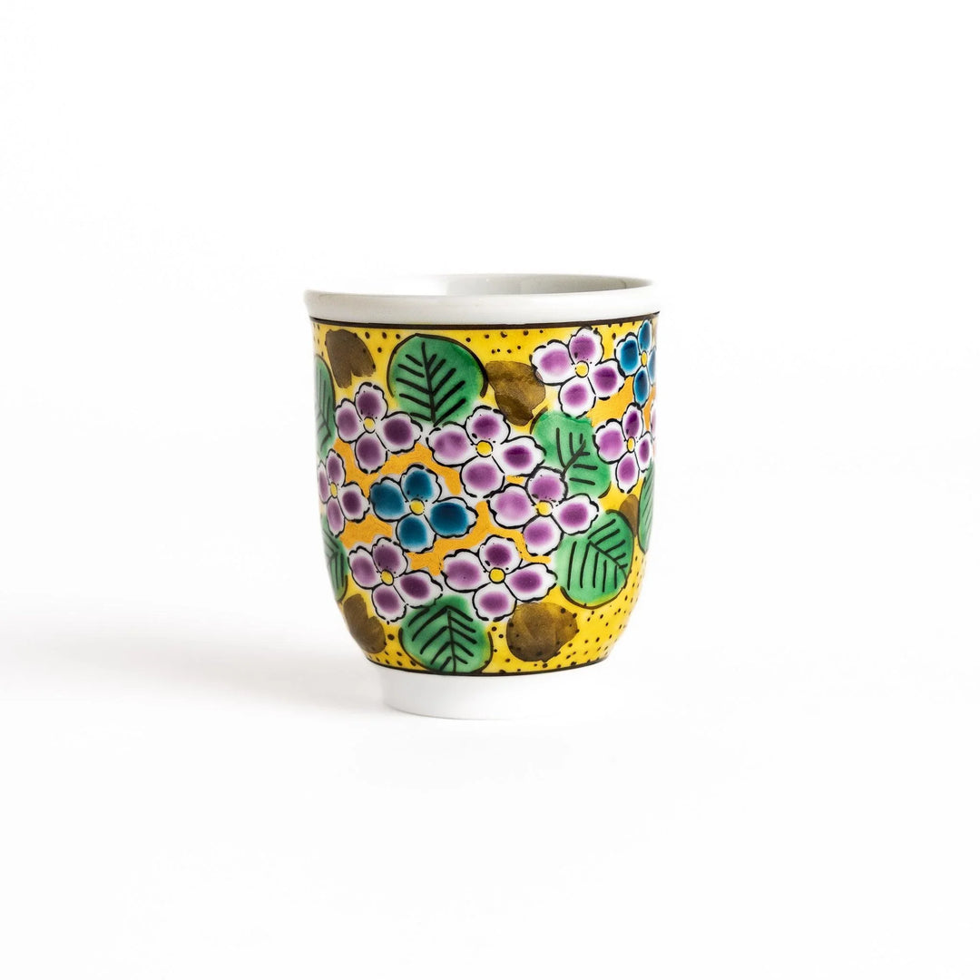 Yellow teacup with a colorful hydrangea pattern and green leaves, perfect for enjoying a cup of tea.