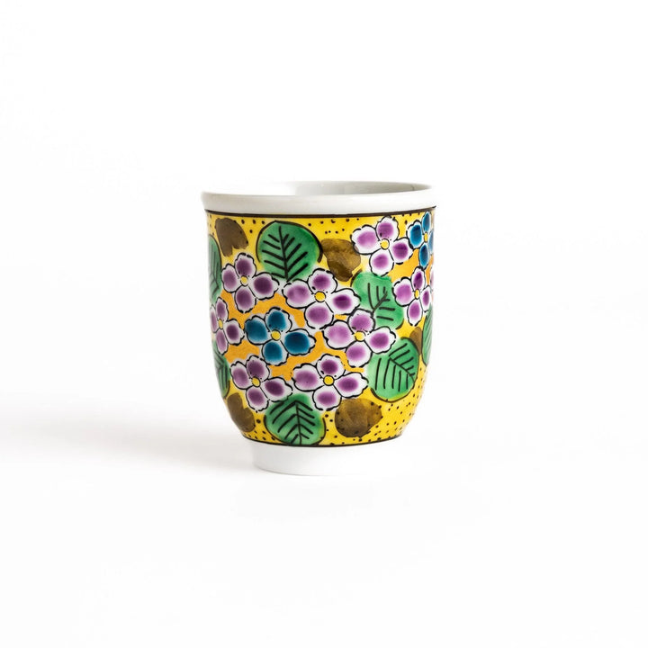Yellow teacup with a colorful hydrangea pattern and green leaves, perfect for enjoying a cup of tea.