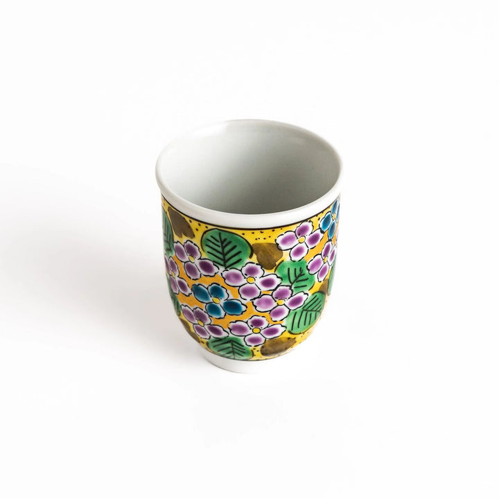 Yellow teacup with a colorful hydrangea pattern and green leaves, perfect for enjoying a cup of tea.