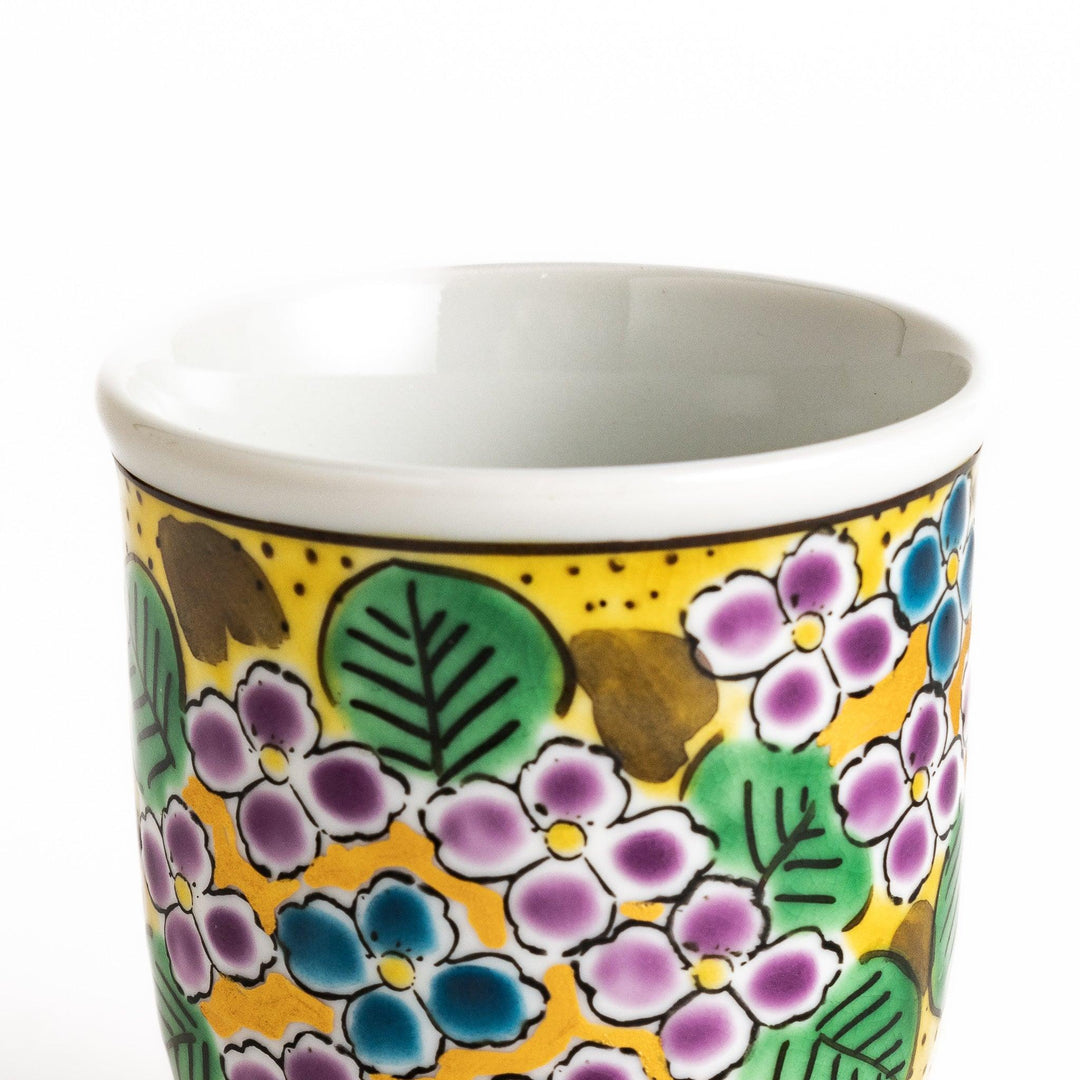 Yellow teacup with a colorful hydrangea pattern and green leaves, perfect for enjoying a cup of tea.