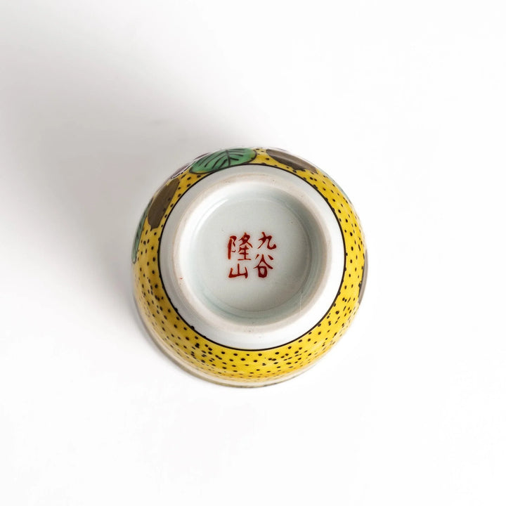 Yellow teacup with a colorful hydrangea pattern and green leaves, perfect for enjoying a cup of tea.