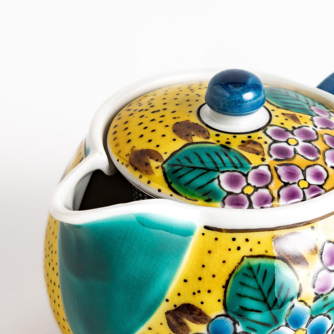 Vibrant yellow ceramic teapot with colorful hydrangea design and green spout for cheerful tea time.
