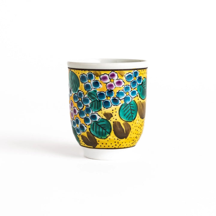 Yellow teacup with a colorful hydrangea pattern and green leaves, perfect for enjoying a cup of tea.