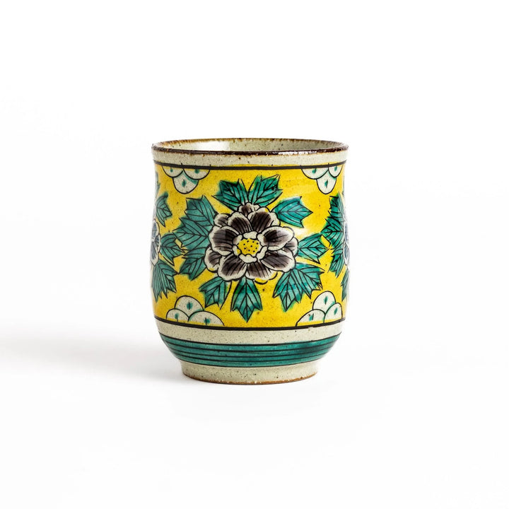 Yellow ceramic teacup with a beautiful floral pattern, featuring a brown rim and a unique base design.