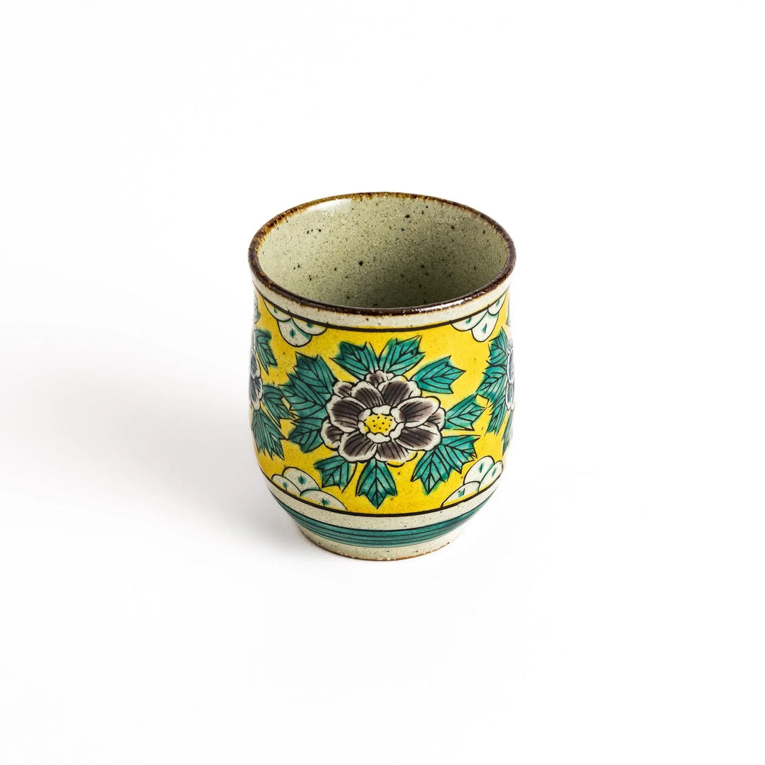 Yellow ceramic teacup with a beautiful floral pattern, featuring a brown rim and a unique base design.