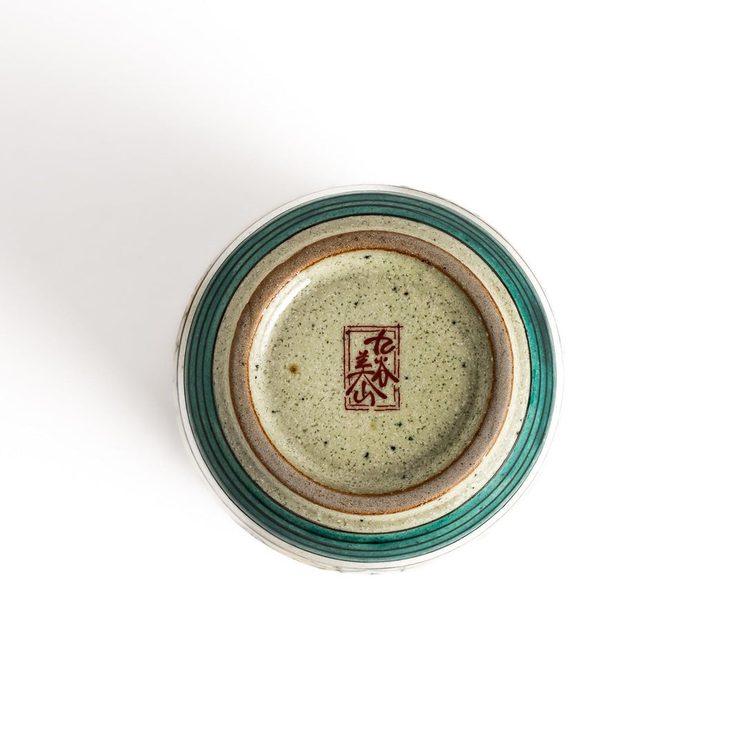 Yellow ceramic teacup with a beautiful floral pattern, featuring a brown rim and a unique base design.