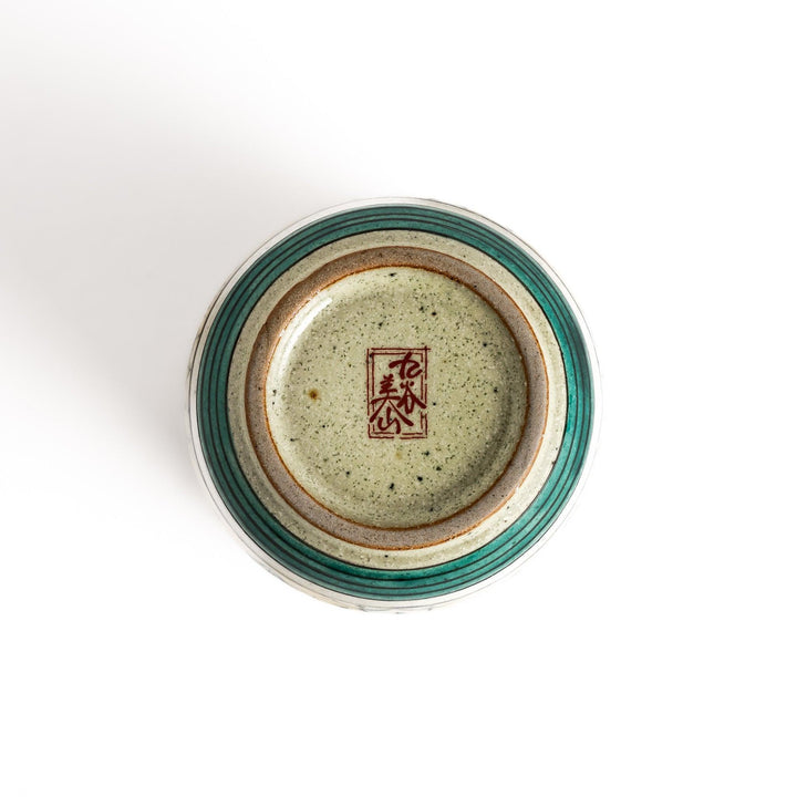 Yellow ceramic teacup with a beautiful floral pattern, featuring a brown rim and a unique base design.