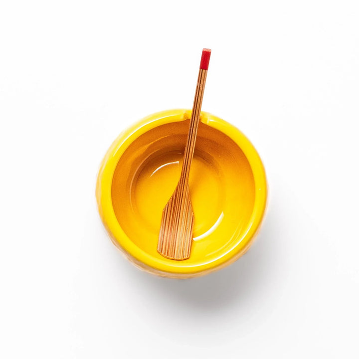 A small ceramic container shaped like a yuzu fruit with a lid and a spoon, bright yellow color.