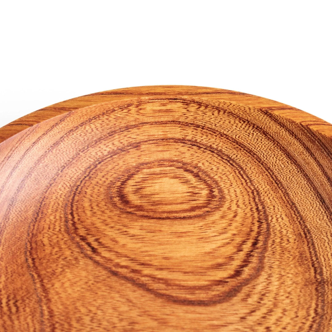 Close-up of the edge of a Zelkova wood salad plate, highlighting the smooth surface and unique swirling grain pattern.